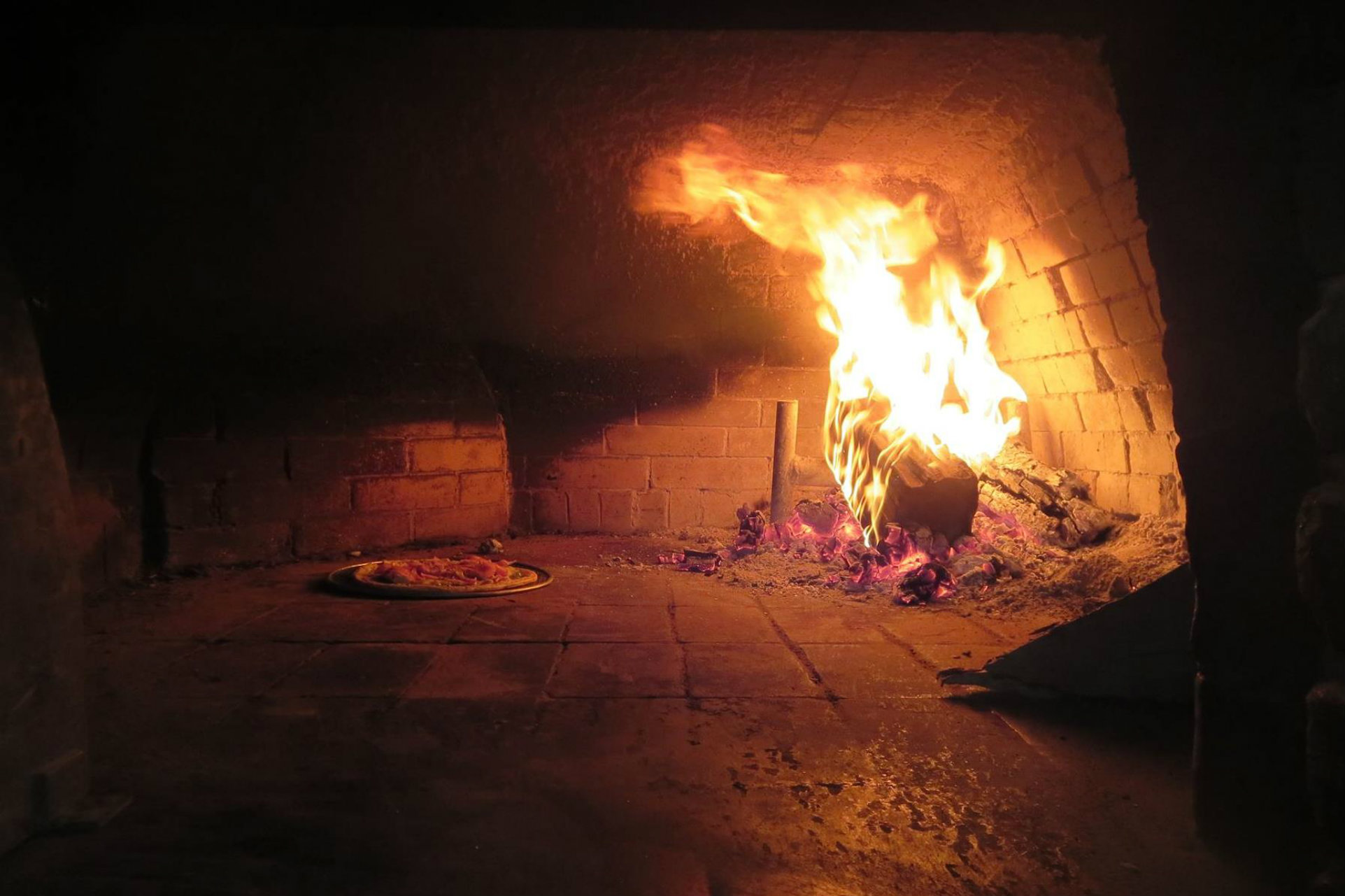 Pizza cooking beside the flames in Terra Cotta Pizzeria’s wood-burning oven